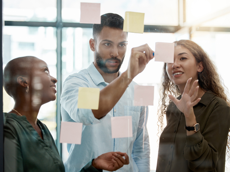 business people posting sticky notes on a wall during a strategy session